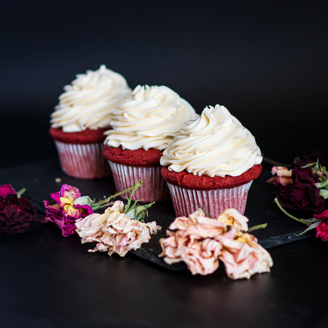 Image of three red-velvet cupcakes topped with swirls of frosting.