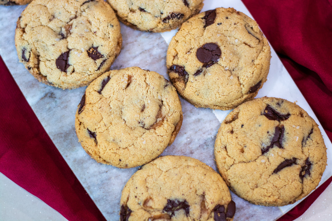 Image of chocolate-chip cookies arranged over a marble slab and table cloth.