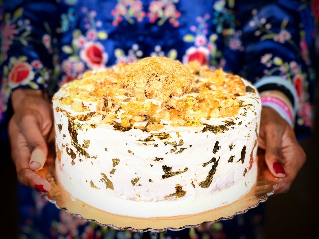 Image of frosted cake decorated with edible gold and spun sugar.