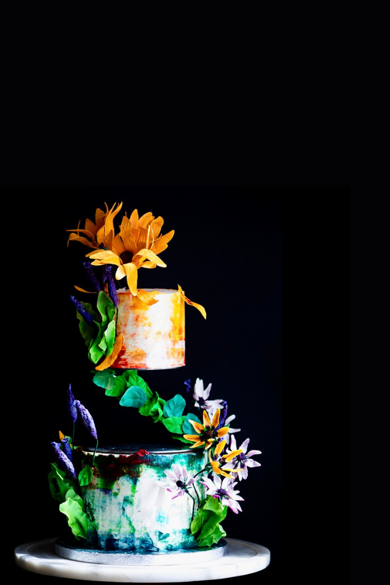 Dramatic photography of a Chipper & Cheeky Spring-themed wedding cake decorated with handmade edible sugar flowers for a dedicated gluten-free luxury wedding in Orange County.