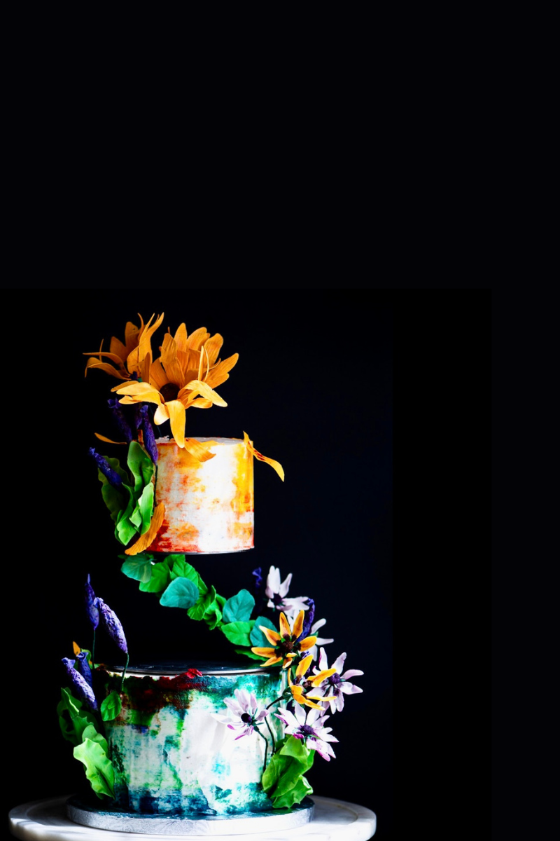 Dramatic photography of a Chipper & Cheeky Spring-themed wedding cake decorated with handmade edible sugar flowers for a dedicated gluten-free luxury wedding in Orange County.