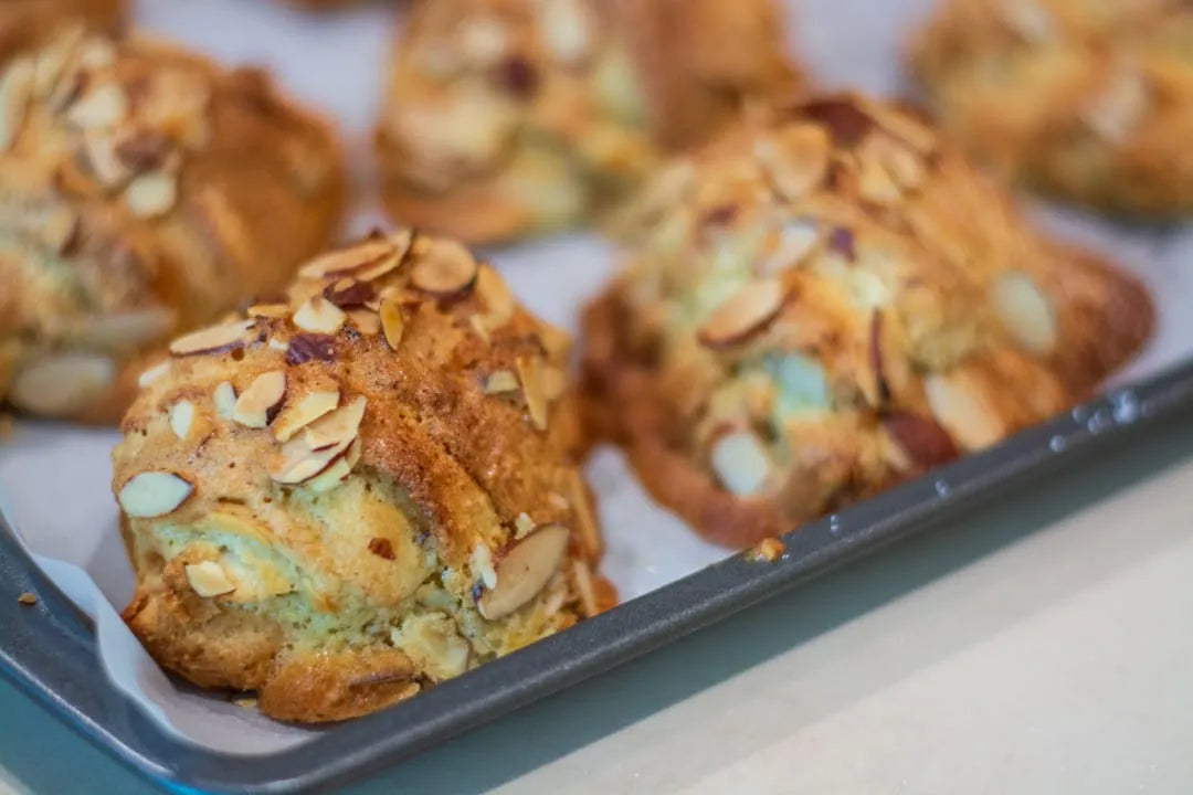 Freshly baked gluten-free almond croissants pastries on a baking sheet lined with parchment paper.