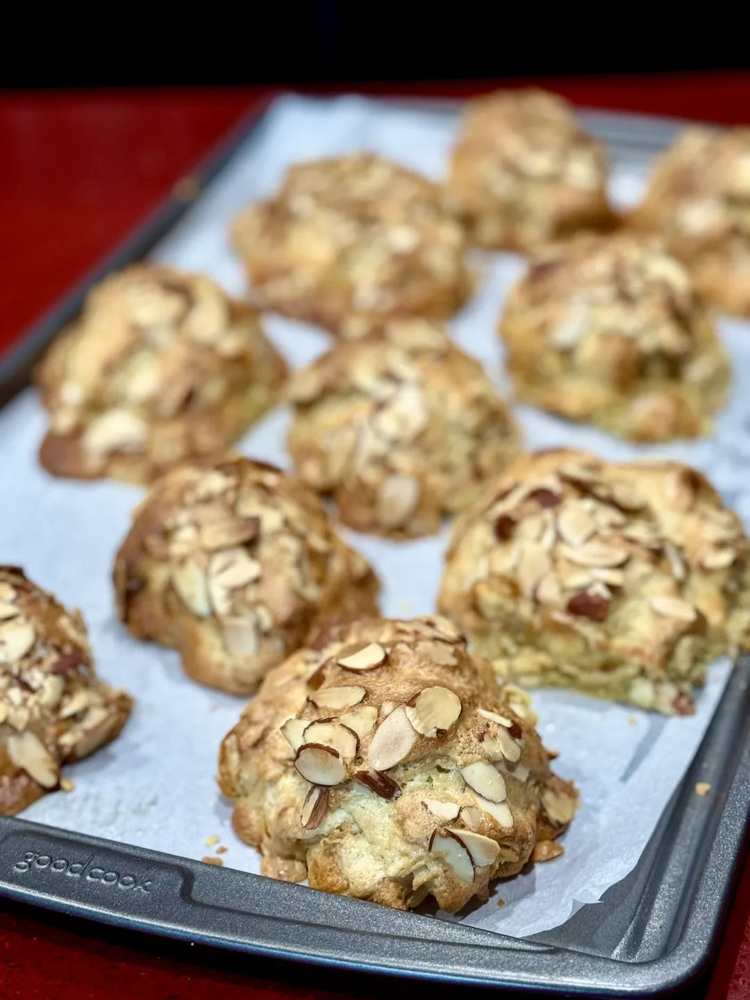 Baked gluten-free almond croissants with almonds on a baking tray.