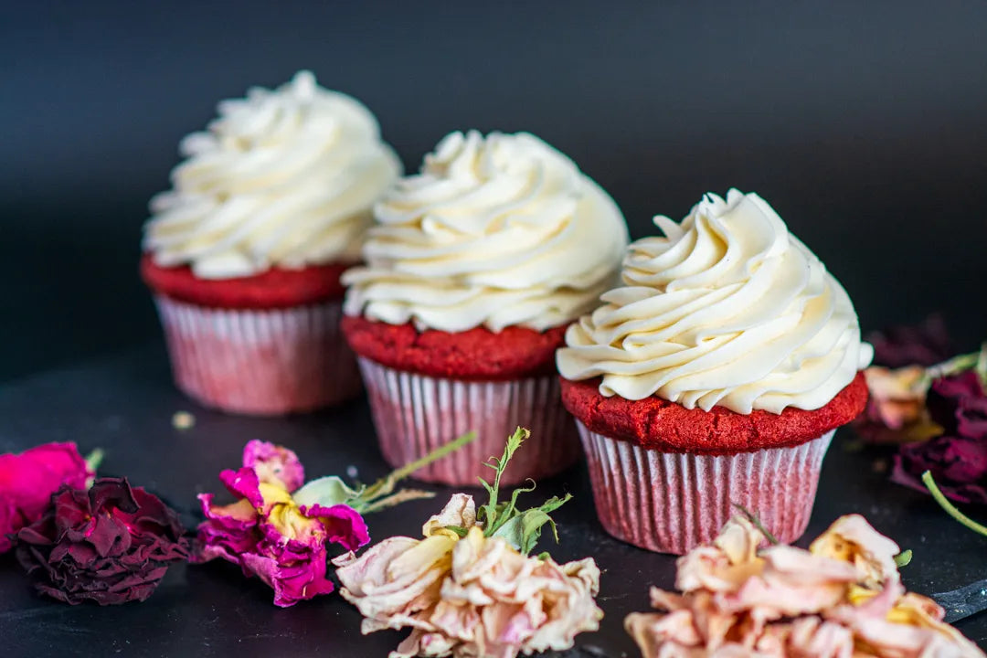 Image of three gluten-free red velvet cupcakes with mounts of cream cheese frosting.