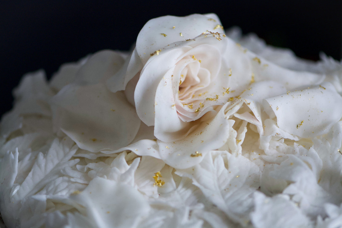 Close-up macro photography of a Chipper & Cheeky white romantic bespoke wedding cake adorned with a winter white rose for a celiac-safe wedding in Orange County.